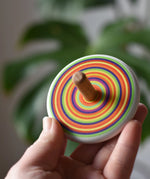 Bajo Colourful Circles Spinning Top in an adult's hand showing the design on the top.