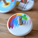 Bajo Echo Spinning Top placed on a wooden surface with other wooden spinning tops in the background. 