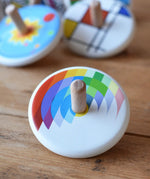 Bajo Echo Spinning Top placed on a wooden surface with other wooden spinning tops in the background. 