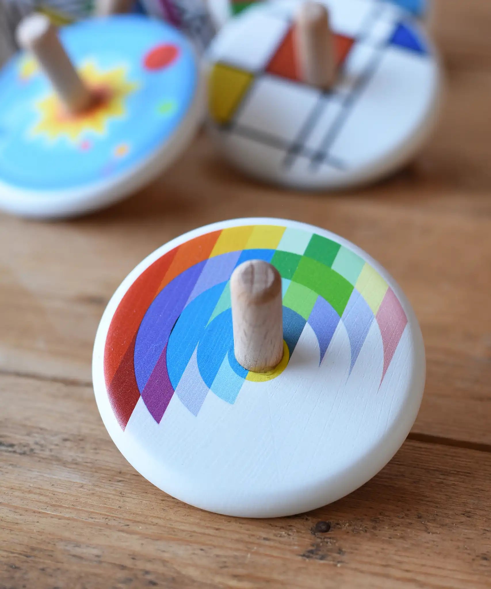 Bajo Echo Spinning Top placed on a wooden surface with other wooden spinning tops in the background. 