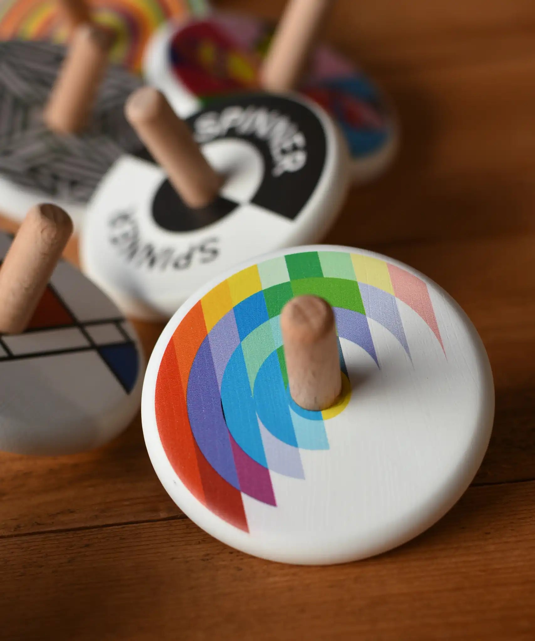 Bajo Echo Spinning Top placed on a wooden surface with other wooden spinning tops in the background. 