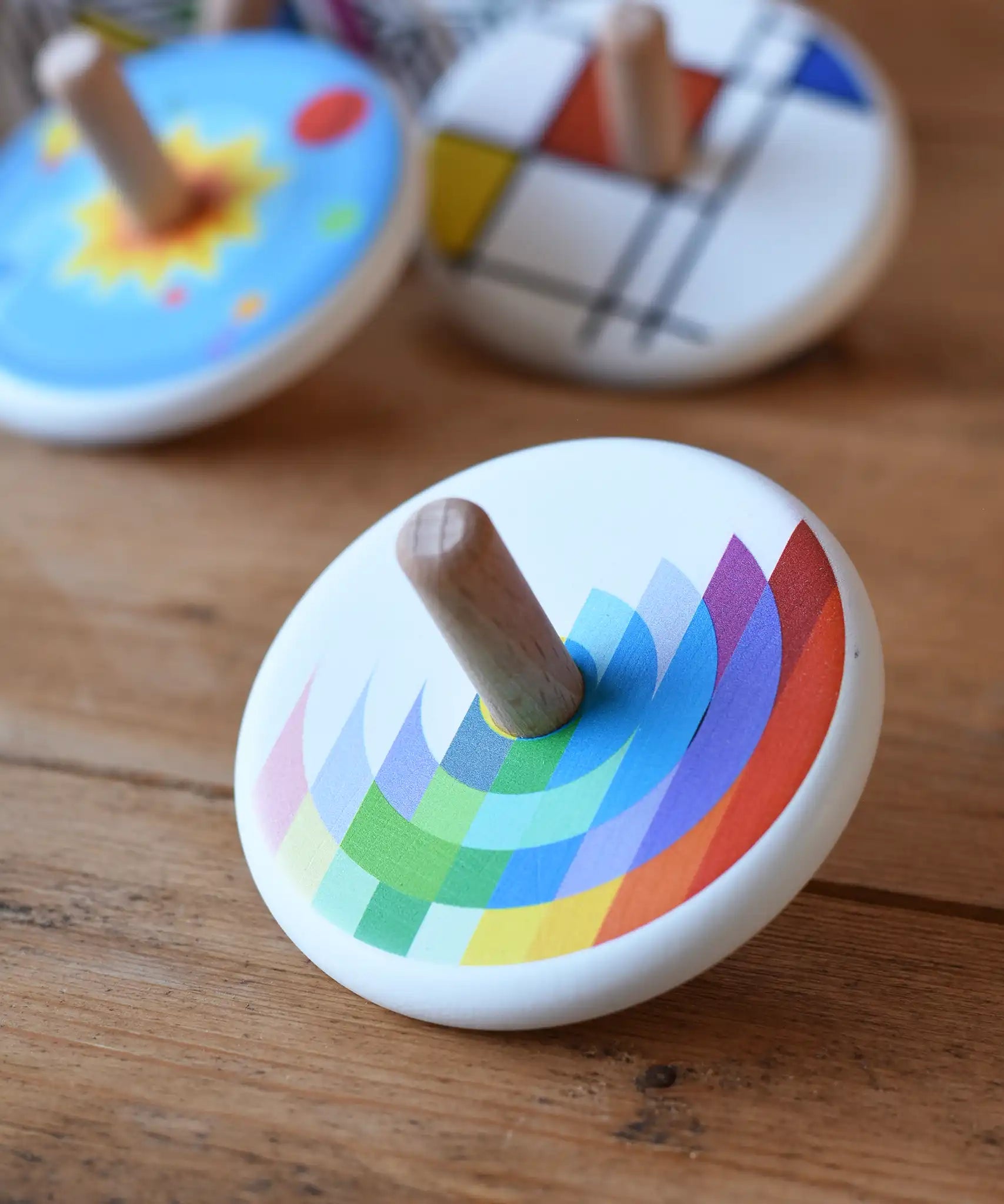 Bajo Echo Spinning Top placed on a wooden surface with other wooden spinning tops in the background. 