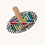 Bajo Modern Colour wooden  Spinning Top toy. A white painted spinning top with a natural wooden stick. The top features a black and white striped design with pops of colour added to some areas.