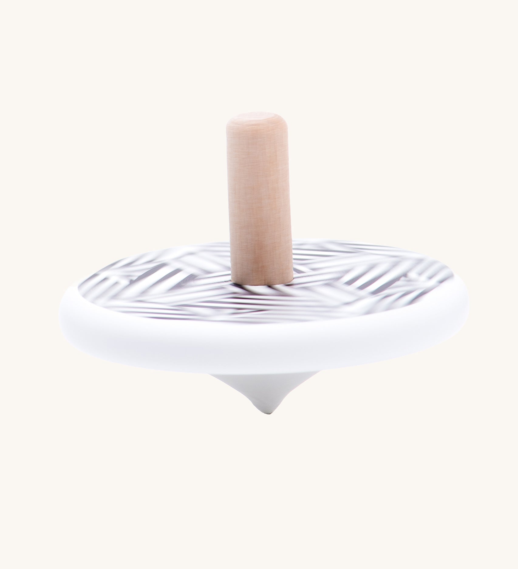 The Bajo Modern wooden Spinning Top toy shown blurred in motion as it spins around. A white painted spinning top with a natural wooden stick. The top features a black and white mono striped design.
