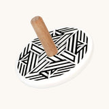 Bajo Modern wooden  Spinning Top toy. A white painted spinning top with a natural wooden stick. The top features a black and white mono striped design.