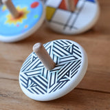 Bajo Modern Spinning Top placed on a wooden surface with other wooden spinning top toys in the background. 