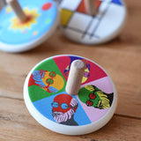 Bajo Pop Art Mr Bajor Spinning Top placed on a wooden surface with other wooden spinning tops in the background. 