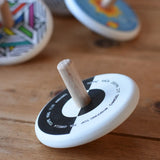 Bajo Languages Spinning Top placed on a wooden surface with other Bajo spinning top s in the background. 
