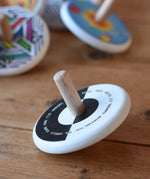 Bajo Languages Spinning Top placed on a wooden surface with other Bajo spinning top s in the background. 