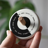 Bajo Languages Spinning Top shown in an adult's hand showing the design printed on the top.