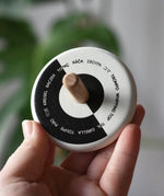 Bajo Languages Spinning Top shown in an adult's hand showing the design printed on the top.
