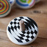 Bajo Latern Spinning Top placed on a wooden surface with other wooden spinning tops in the background.
