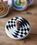 Bajo Latern Spinning Top placed on a wooden surface with other wooden spinning tops in the background.