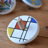 Bajo Mondrian Spinning Top placed on a wooden surface.