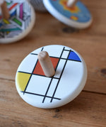 Bajo Mondrian Spinning Top placed on a wooden surface.