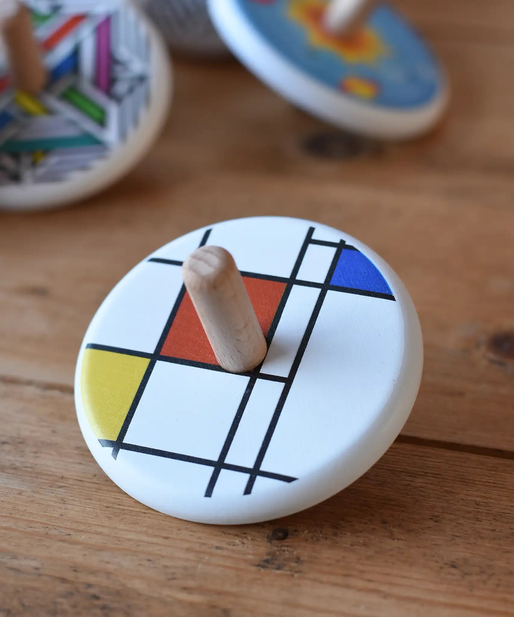 Bajo Mondrian Spinning Top placed on a wooden surface.