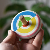 Bajo Colourful Semi Circles Spinning Top in an adult's hand showing the design on top.