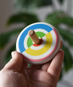 Bajo Colourful Semi Circles Spinning Top in an adult's hand showing the design on top.