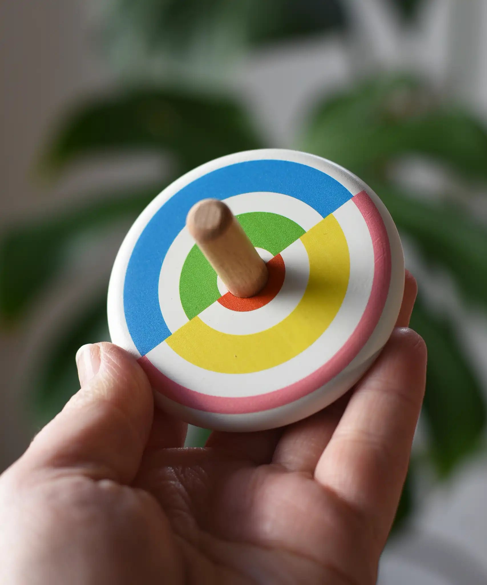 Bajo Colourful Semi Circles Spinning Top in an adult's hand showing the design on top.
