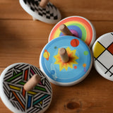 Bajo Universe Spinning Top placed on a wooden surface surrounded by other design of Bajo wooden spinning tops. 