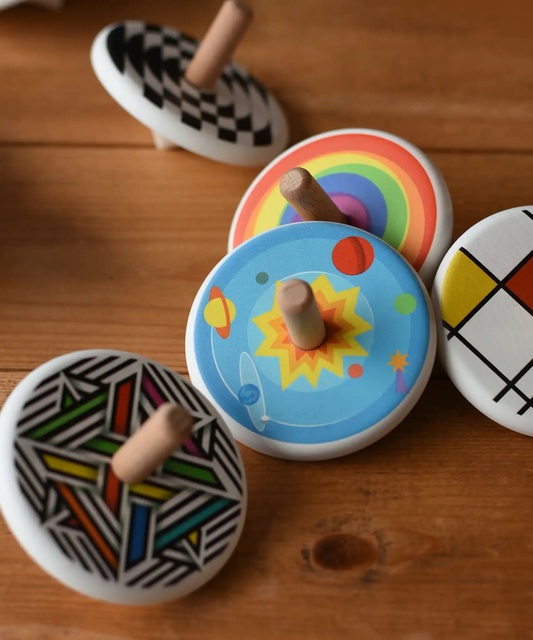 Bajo Universe Spinning Top placed on a wooden surface surrounded by other design of Bajo wooden spinning tops. 