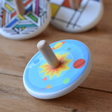 Bajo Universe Spinning Top placed on a wooden surface with other wooden spinning tops in the background.