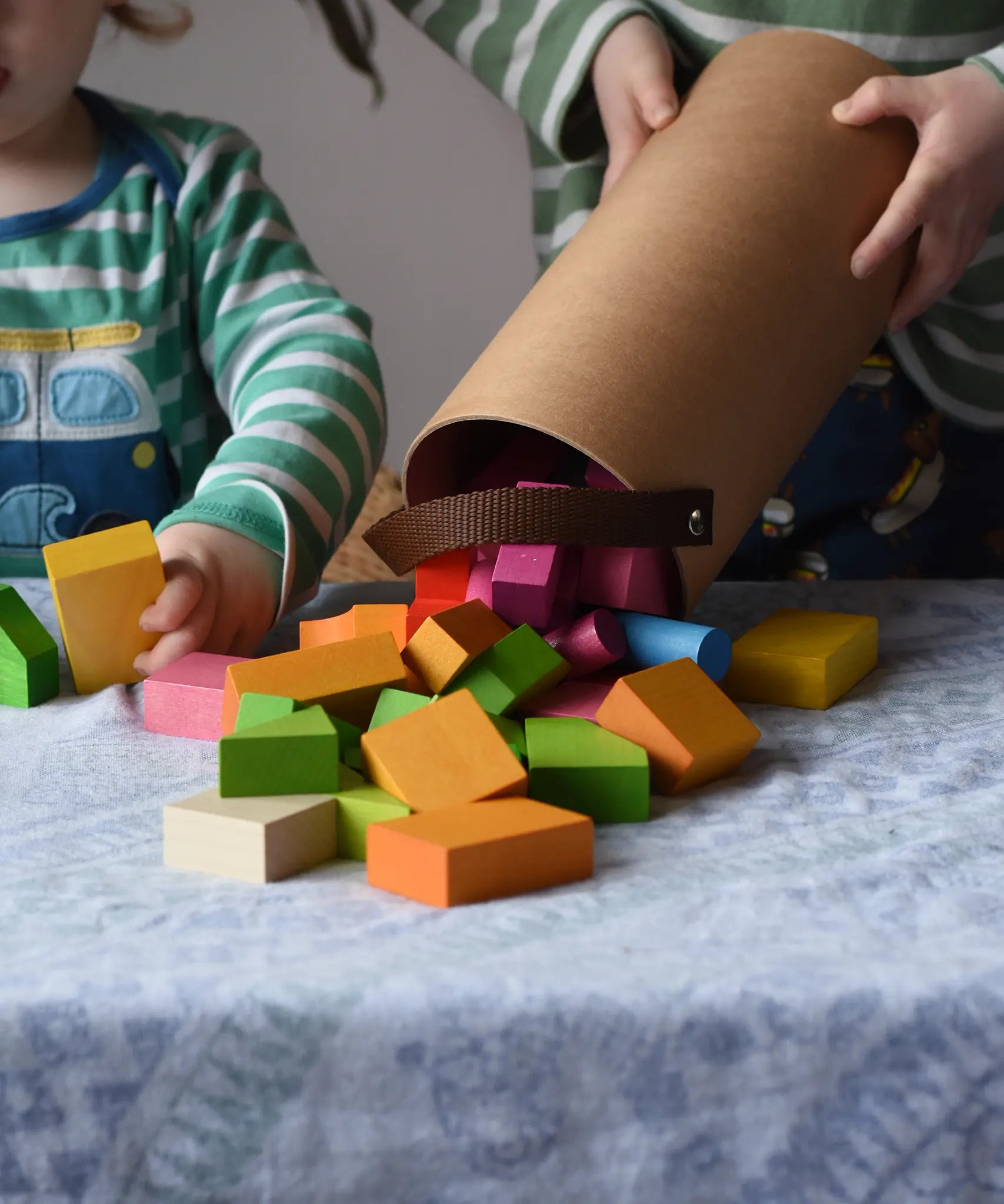 Bajo 43 wooden building blocks. 43 blocks, in 16 different shapes and 10 colours. Child tipping blocks from the sturdy cylinder shaped storage box.