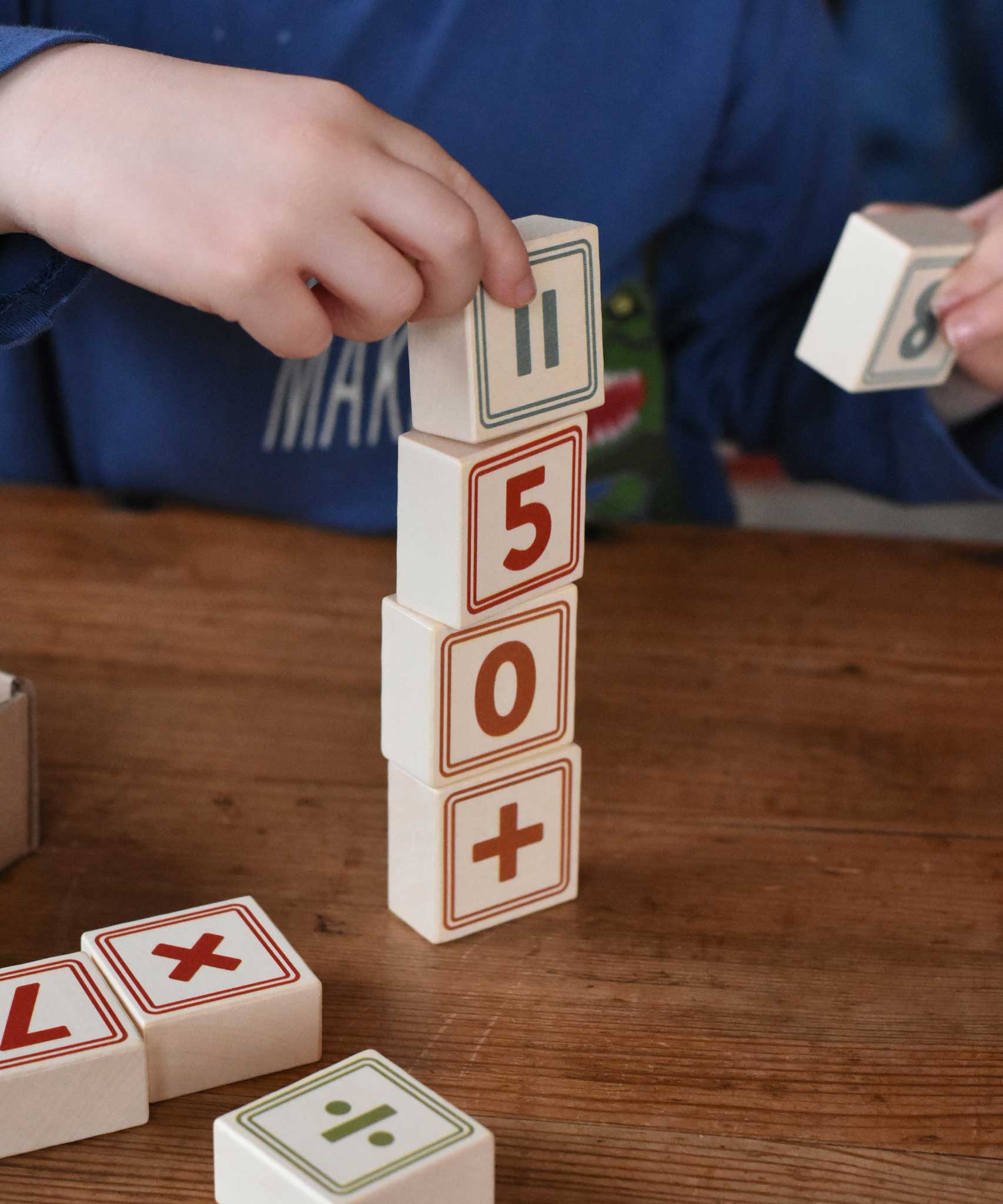 A child stacking up blocks from the Bajo 40 Numbers & Symbols Blocks set on top of each other. These heirloom quality toys by Bajo are part of a wide range of wooden toys available here at Babipur. 