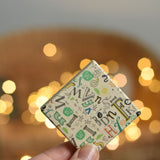 An adult holding up a tile from the Bajo Wooden Tiles Memory Game. The tiles have an illustration on one side and a mix of letters in different fonts on the other. These heirloom quality toys by Bajo are part of a wide range of wooden toys available here at Babipur.