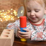 A child playing with the Bajo Deep And Shallow Sorter wooden toy placed on a small wooden table. The child is stacking the cylinder shaped blocks on top of each other. These heirloom quality toys by Bajo are part of a wide range of wooden toys available here at Babipur. 