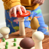 A close up of a child's hand grabbing the red fly agaric mushroom from the Bajo Wooden Mushroom Forest Peg Puzzle set. These heirloom quality toys by Bajo are part of a wide range of wooden toys available here at Babipur. 
