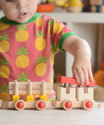 Child putting the red removable roof piece on the Bajo train carriage