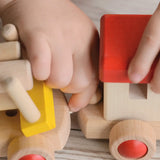 Child connecting two carriages with an elastic thread looping over a wooden dowel