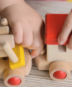 Child connecting two carriages with an elastic thread looping over a wooden dowel