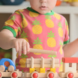 Child stacking log pieces on a carriage from the Bajo wooden train to build set