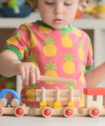 Child stacking log pieces on a carriage from the Bajo wooden train to build set