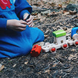 Child on the floor building a Bajo wooden train. 