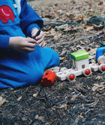 Child on the floor building a Bajo wooden train. 