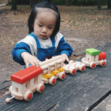 Child playing with the Bajo wooden train to build set on a table in the park 
