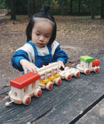 Child playing with the Bajo wooden train to build set on a table in the park 