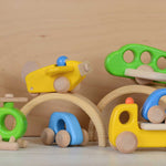 A collection of Bajo planes and vehicles stacked on and around pieces of a Grimm's natural rainbow