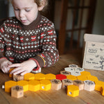 Child playing with the Bajo plastic-free stacking wooden hive blocks on a wooden table