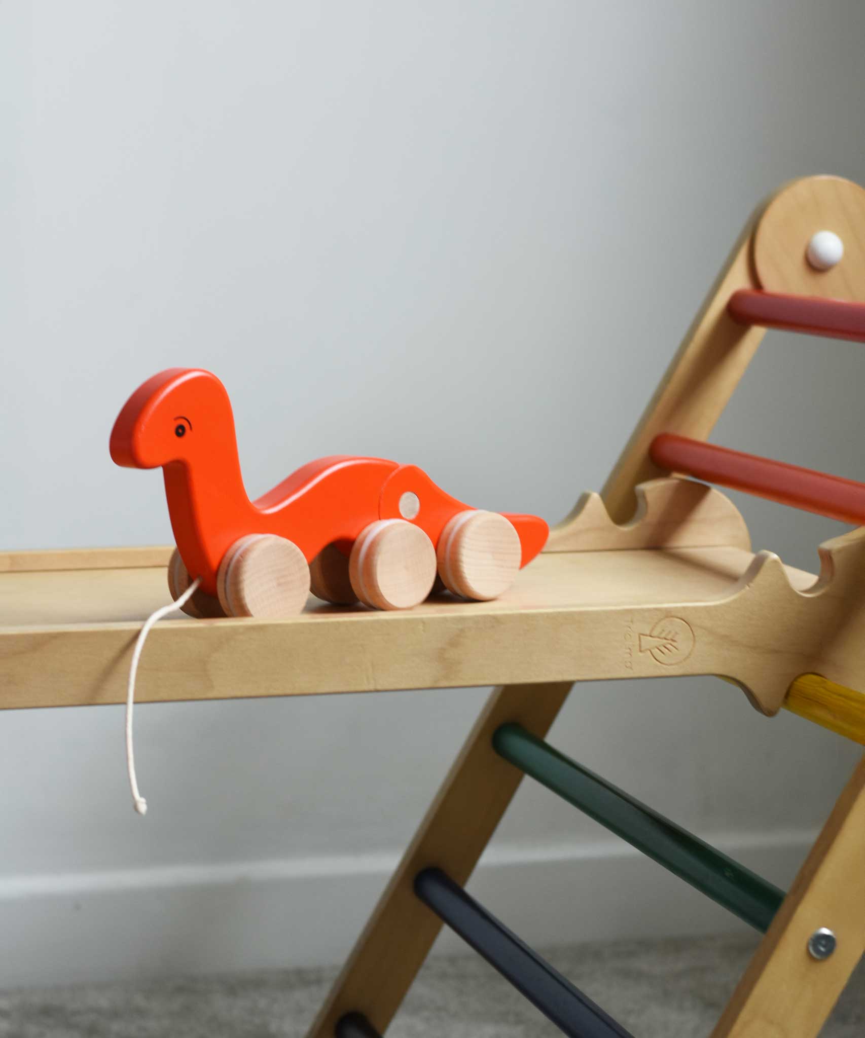 A red coloured Bajo wriggling worm pull along toy placed on a Triclimb Miri slide. These heirloom quality toys by Bajo are part of a wide range of wooden toys available here at Babipur. 