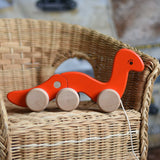 A red Bajo wriggling worm pull along toy placed on a child's wicker chair. These heirloom quality toys by Bajo are part of a wide range of wooden toys available here at Babipur.  