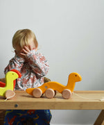A child playing peek-a-book, hiding behind his hands. There are three Bajo wooden wriggling worm pull along toy placed on a Miri slide in front of them. These heirloom quality toys by Bajo are part of a wide range of wooden toys available here at Babipur. 