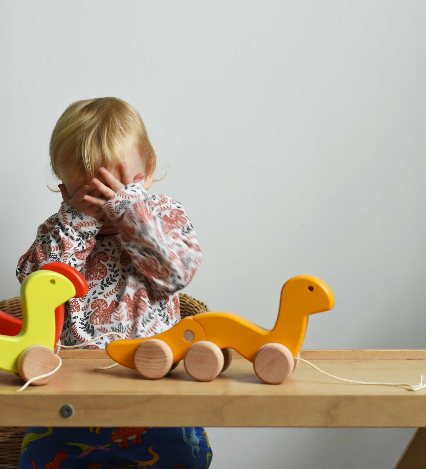 A child playing peek-a-book, hiding behind his hands. There are three Bajo wooden wriggling worm pull along toy placed on a Miri slide in front of them. These heirloom quality toys by Bajo are part of a wide range of wooden toys available here at Babipur. 