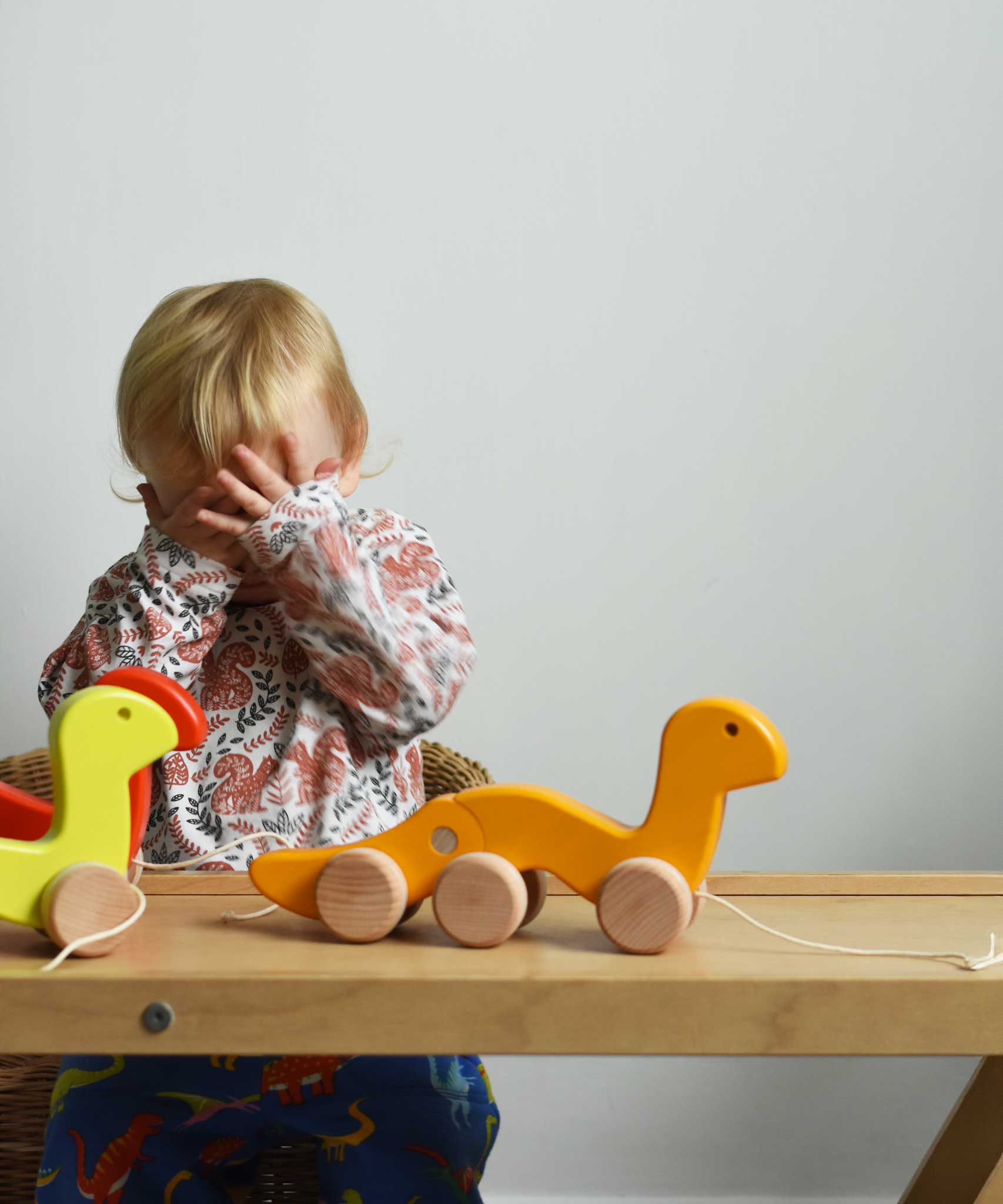 A child playing peek-a-book, hiding behind his hands. There are three Bajo wooden wriggling worm pull along toy placed on a Miri slide in front of them. These heirloom quality toys by Bajo are part of a wide range of wooden toys available here at Babipur. 