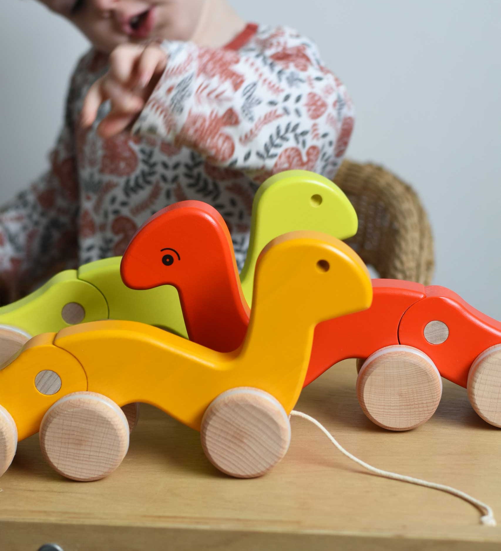 Three Bajo pull along wriggling worms toys placed on a Triclimb Miri. A child can be seen in the background. These heirloom quality toys by Bajo are part of a wide range of wooden toys available here at Babipur. 