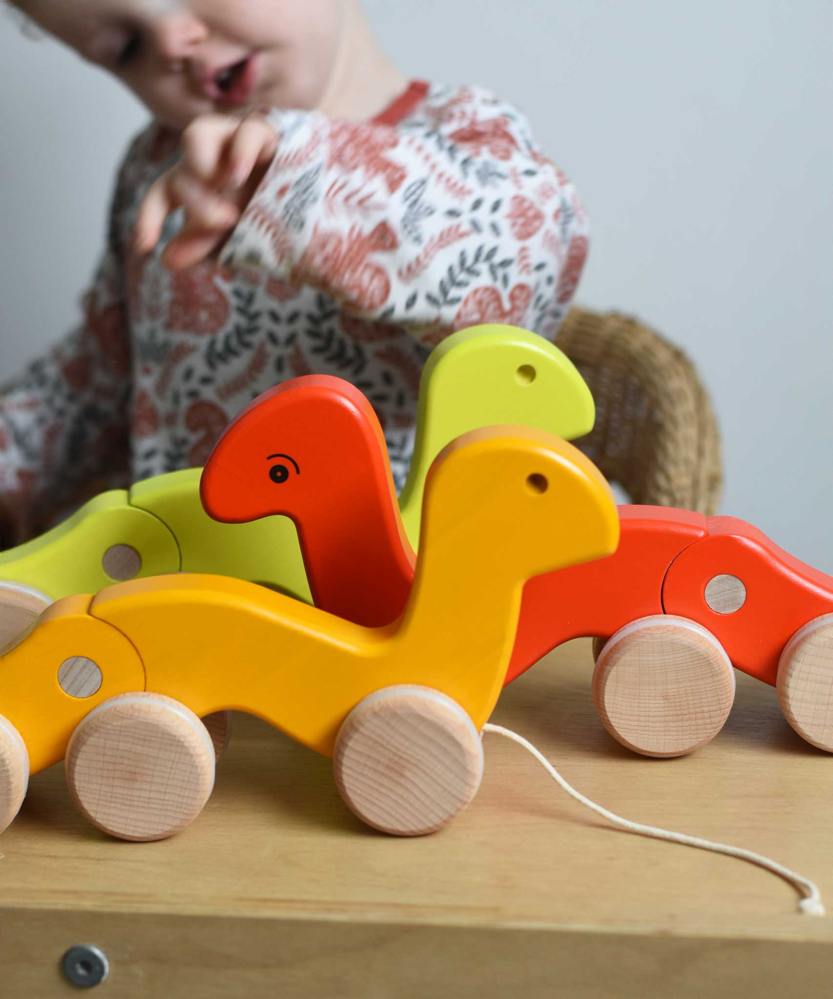 Three Bajo pull along wriggling worms toys placed on a Triclimb Miri. A child can be seen in the background. These heirloom quality toys by Bajo are part of a wide range of wooden toys available here at Babipur. 