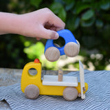 Bajo yellow breakdown lorry wooden toy with a child's hand lifting the blue car off the trailer.